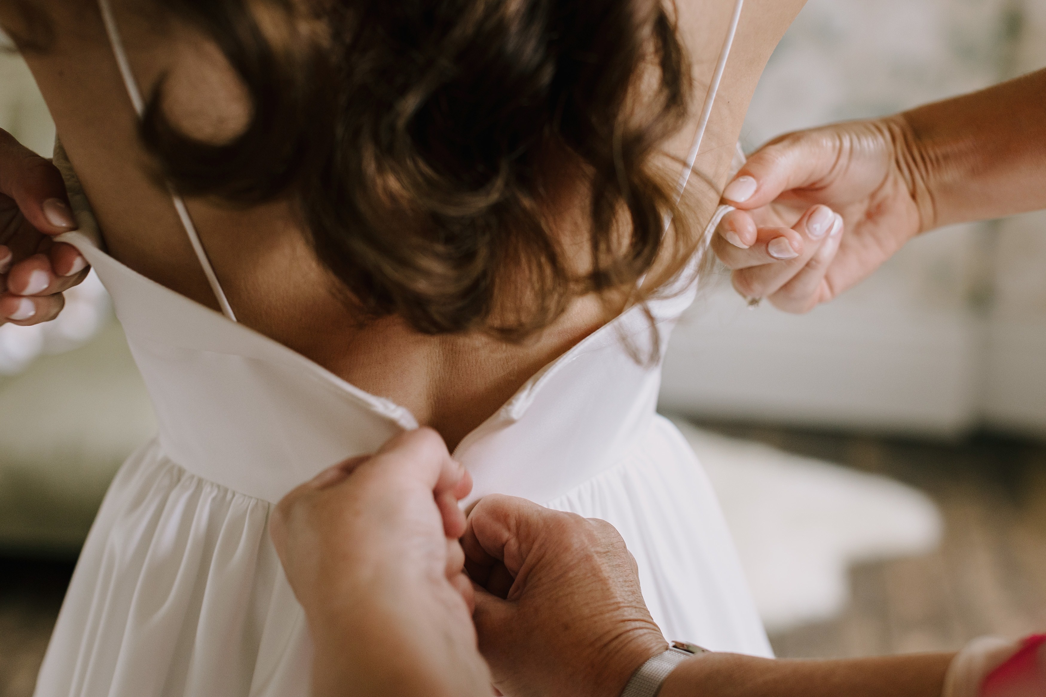 Bride being zipped into her wedding dress