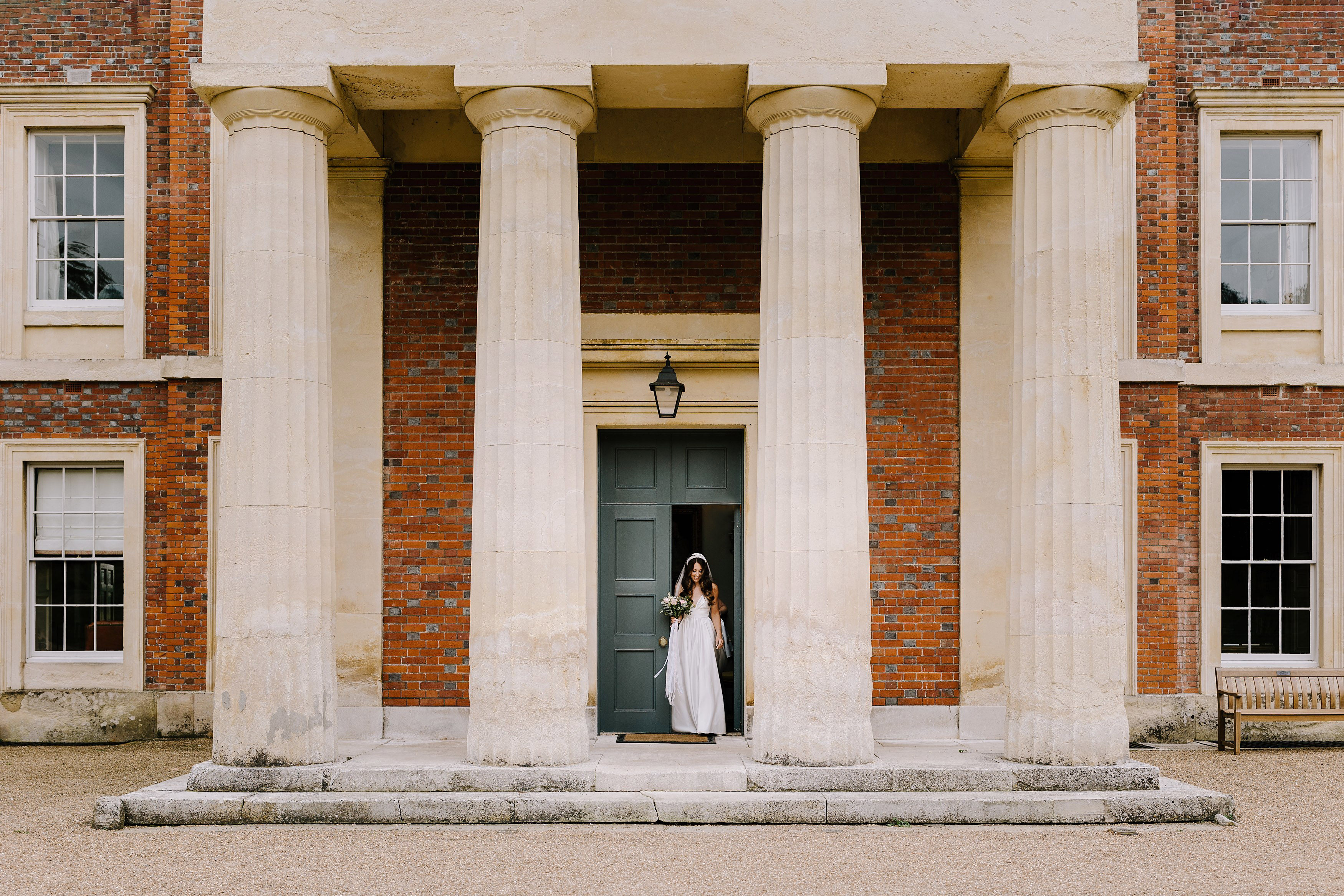 Bride walking out of Goodnestone House, through the portico on the way to her wedding