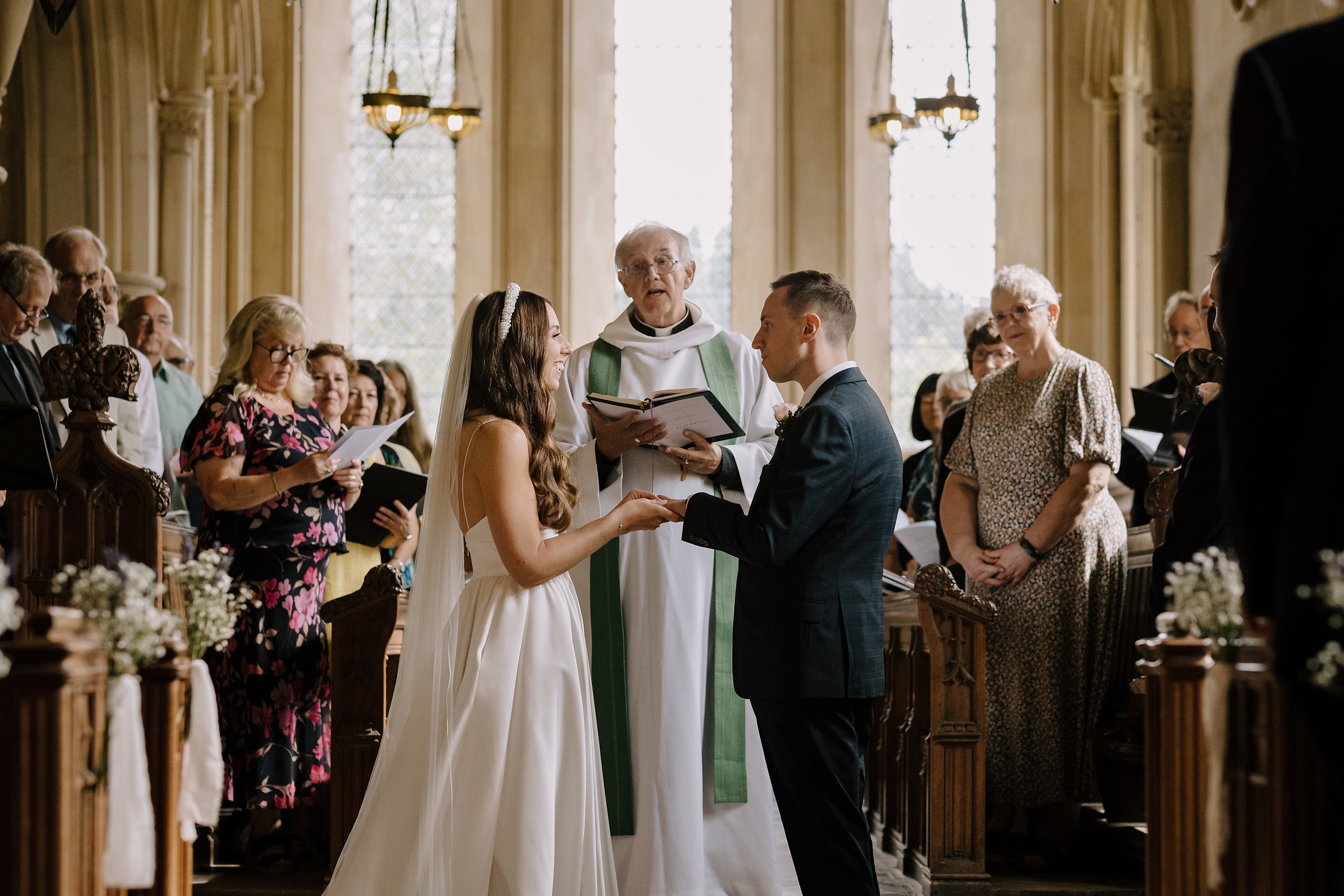 Bride and groom face each other as they are led through their vows by the vicar