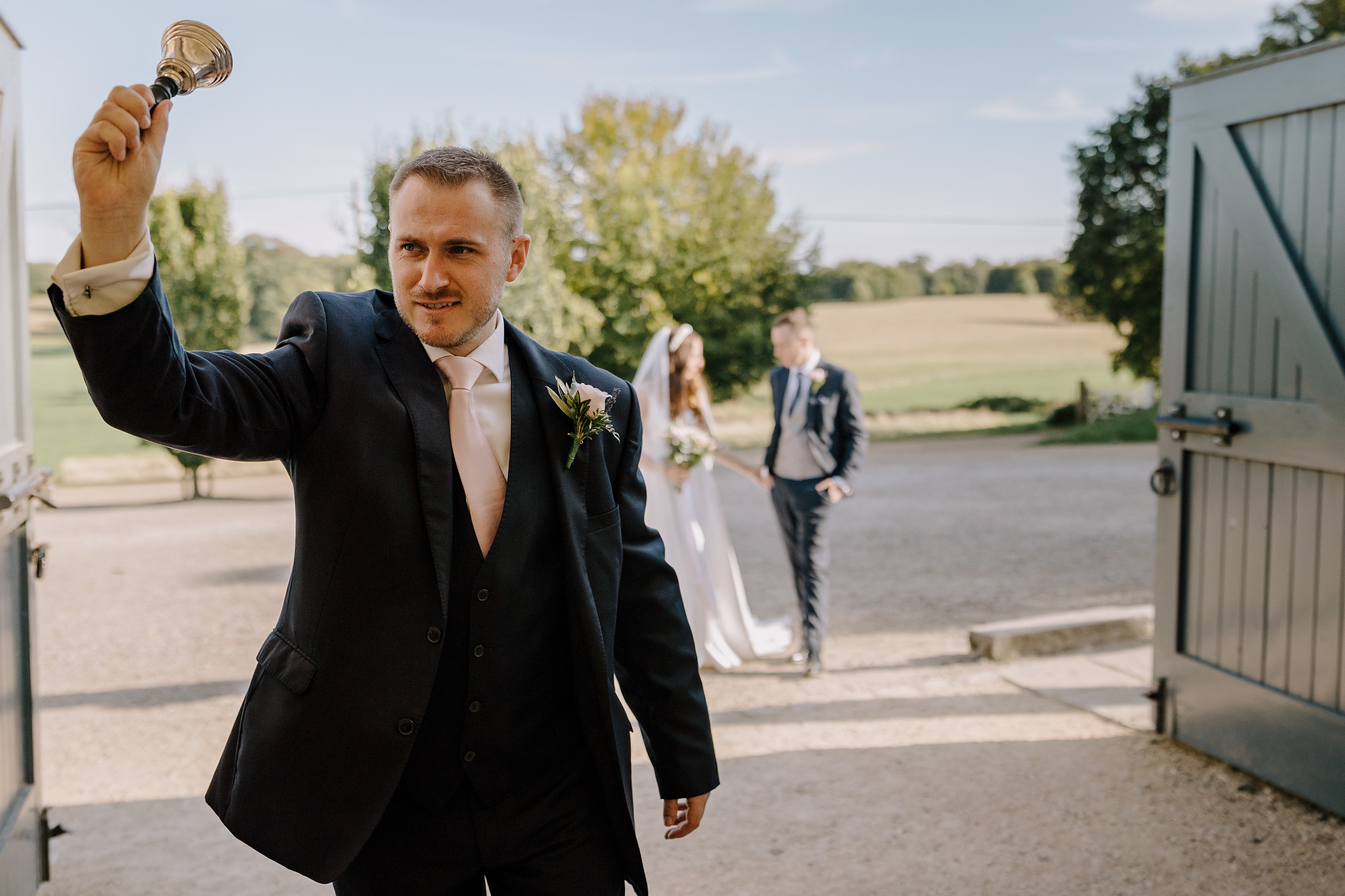 A groomsman ringing a bell to announce the arrival of the bride and groom to the wedding reception