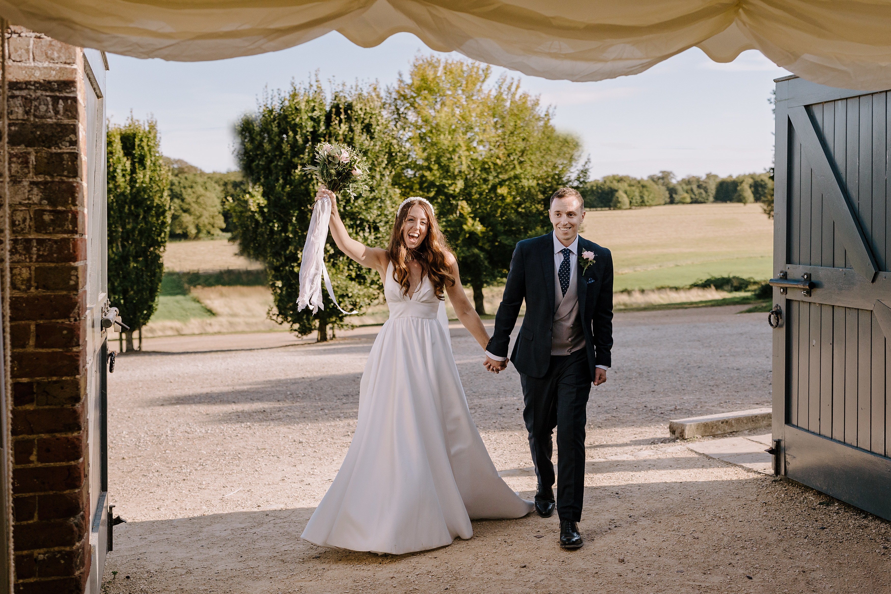 a bride and groom entering their wedding reception looking excited