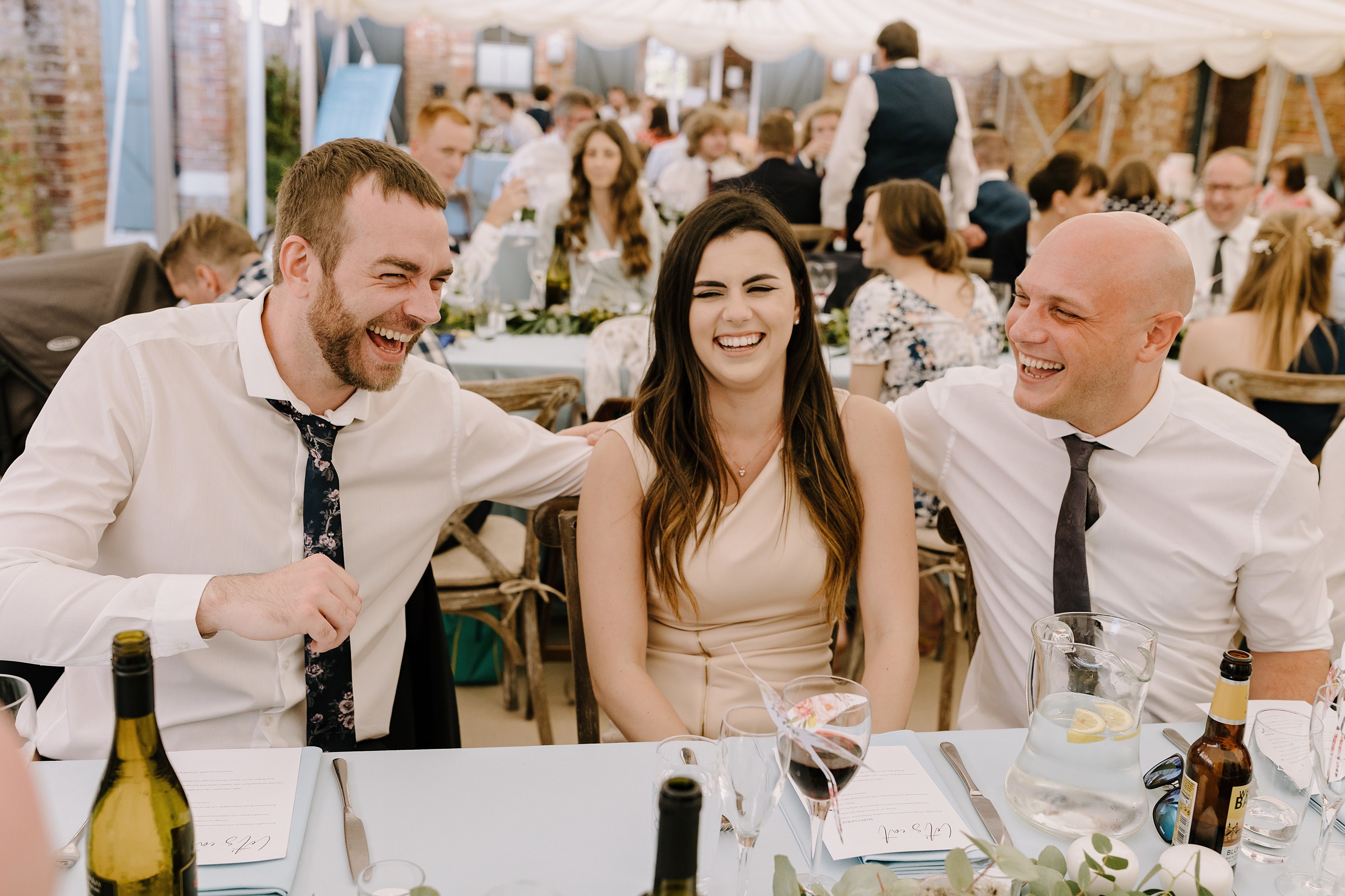 Wedding guests laughing together whilst sat at their table