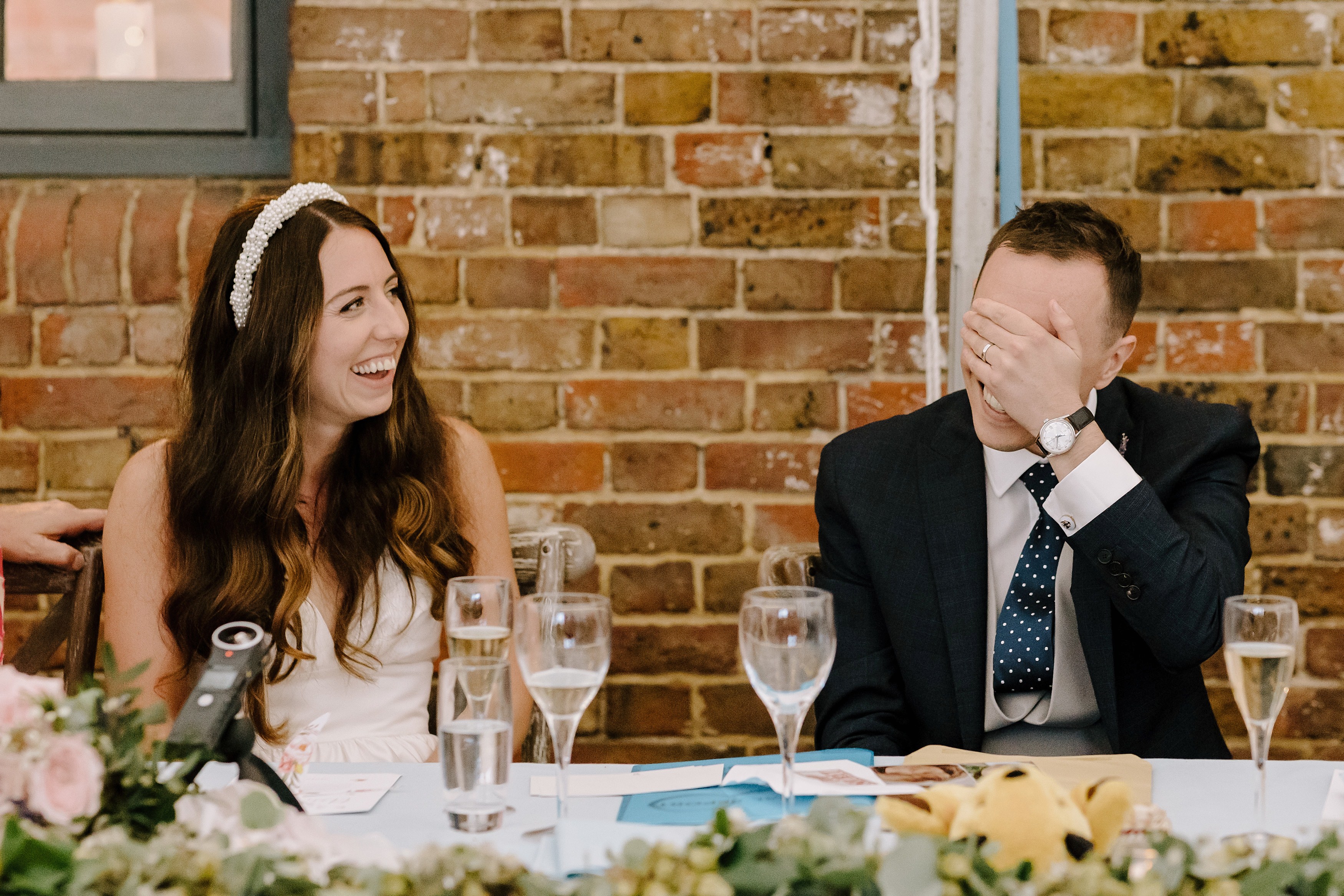 The bride and groom laughing during the wedding speeches