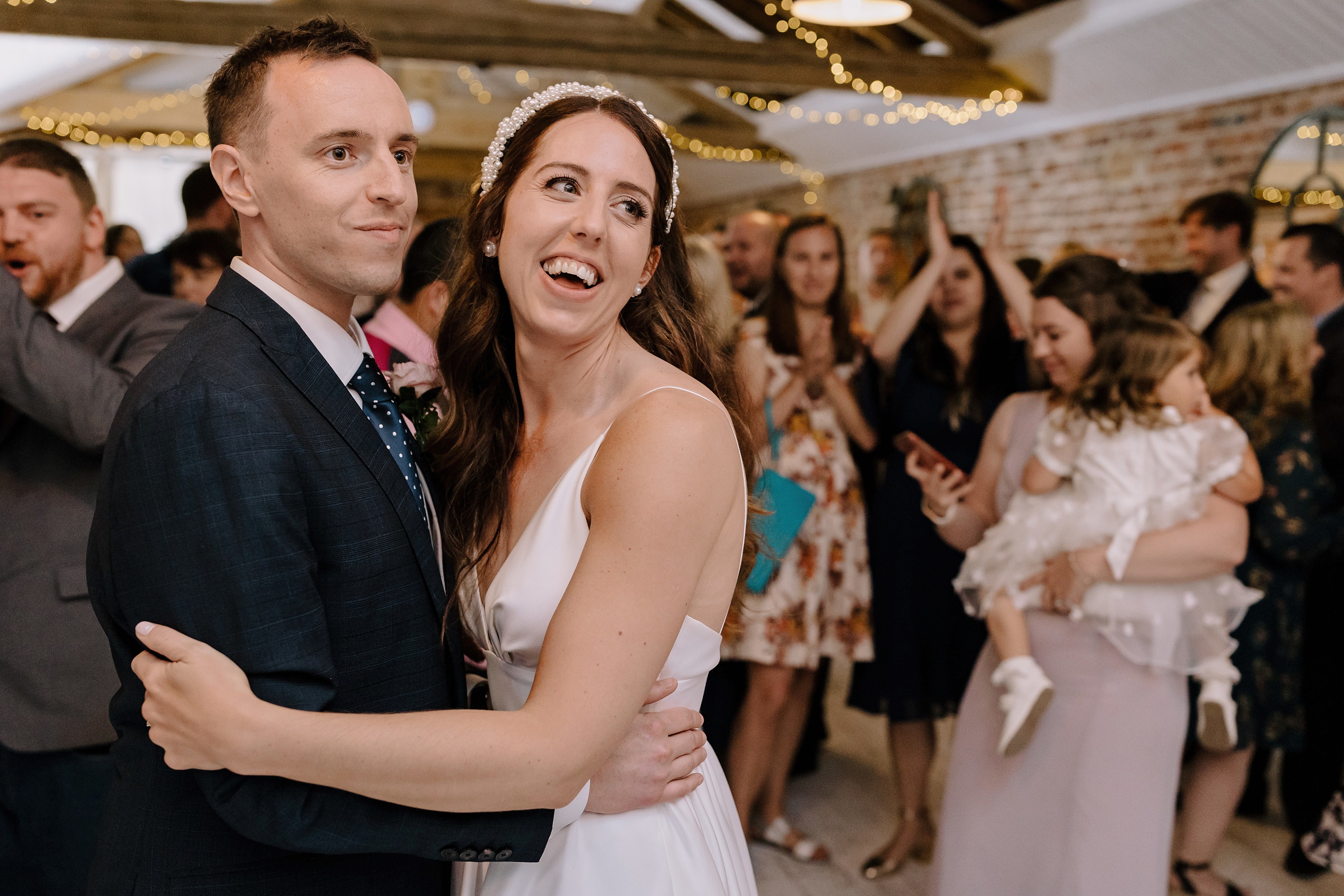 The bride and groom hugging and smiling at something in the background