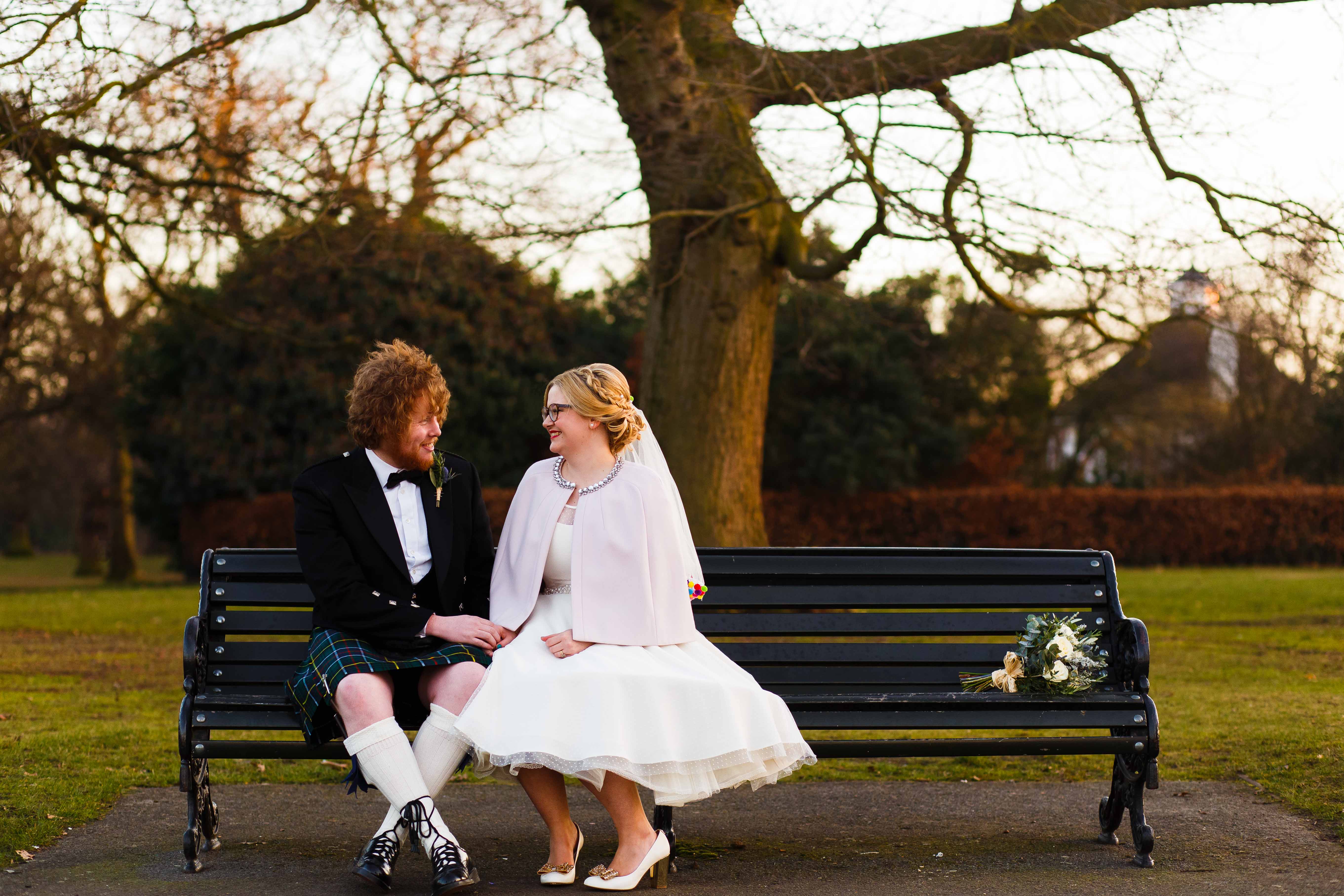 Marries couple sit on bench during their wedding portraits