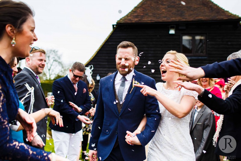 Couple laughing as they have confetti thrown at them. 