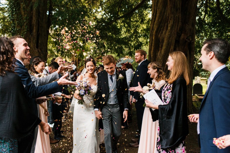 Newlyweds walking out of a church as confetti is thrown at them